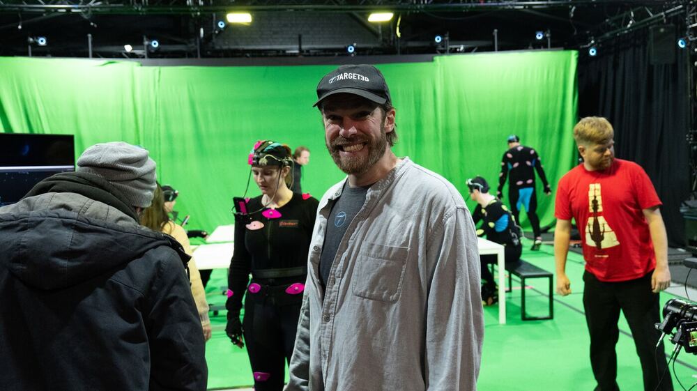 Performers in mocap suits on a green screen stage with Ashley in the middle